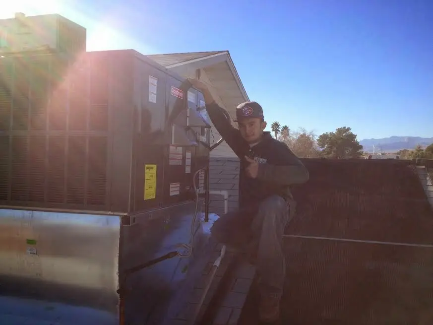 HVAC technician performing AC Tune-Up on a rooftop unit in Lindsay