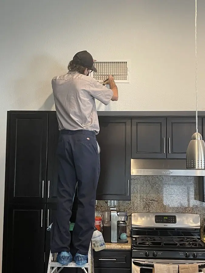Technician inspecting an air vent during HVAC service in Lindsay